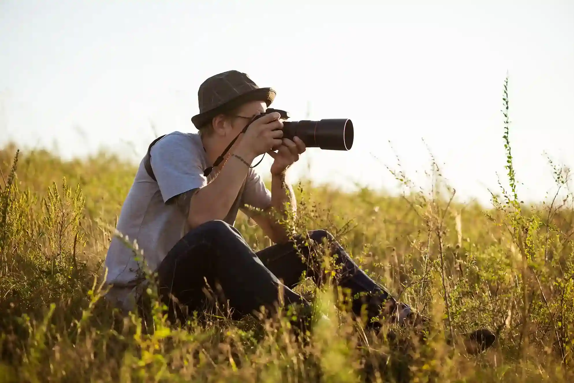 Fotógrafo con teleobjetivo en el bosque al amanecer, un ciervo al fondo